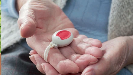 Hand mit dem roten wasserdichten Notrufknopf von WOHNRUF
